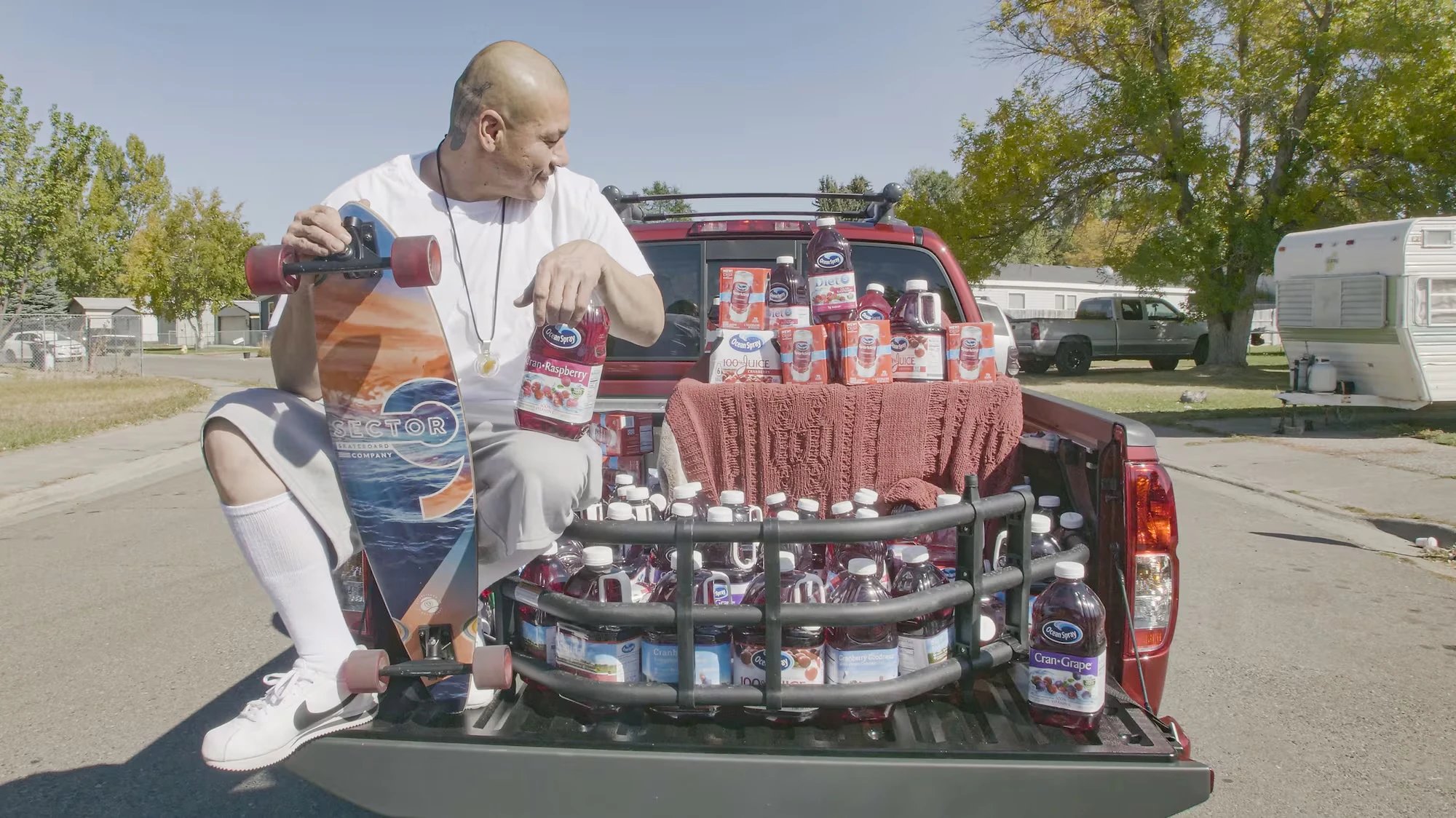 Nathan Apodaca with his longboard on the tailgate of the cranberry-red truck Ocean Spray gifted him, loaded with juice